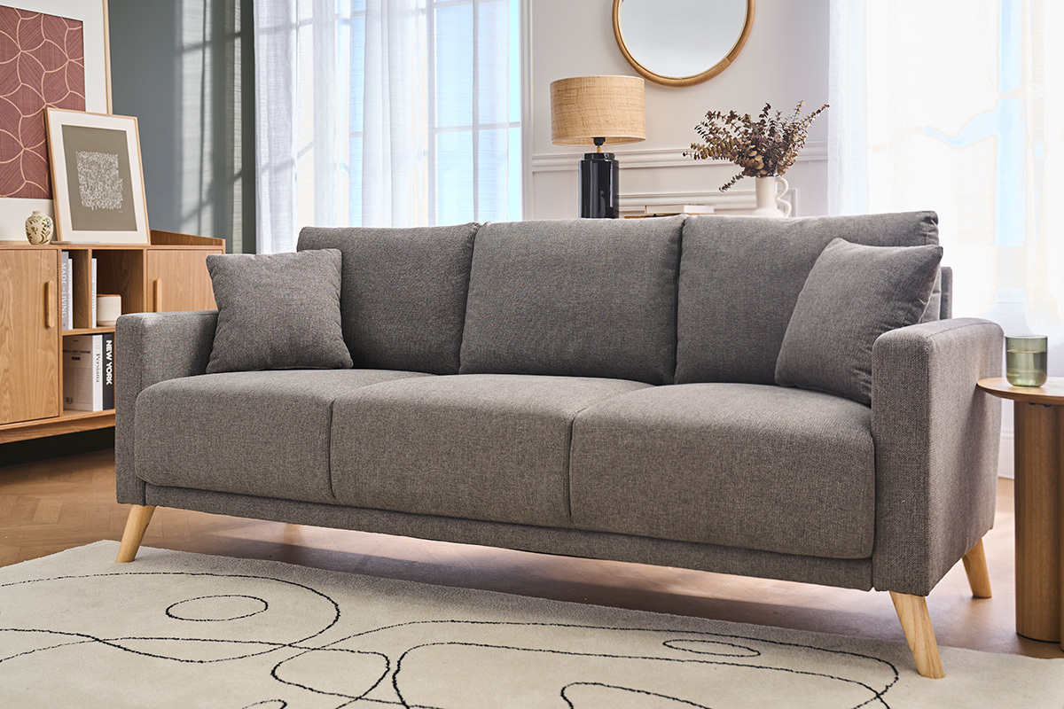 Canap� 3 places en tissu gris, pieds en bois clair, dans un salon avec meubles en bois.