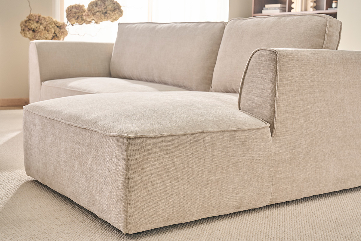 Canap� d'angle droit beige en tissu velours textur�, vue de c�t� dans un salon.