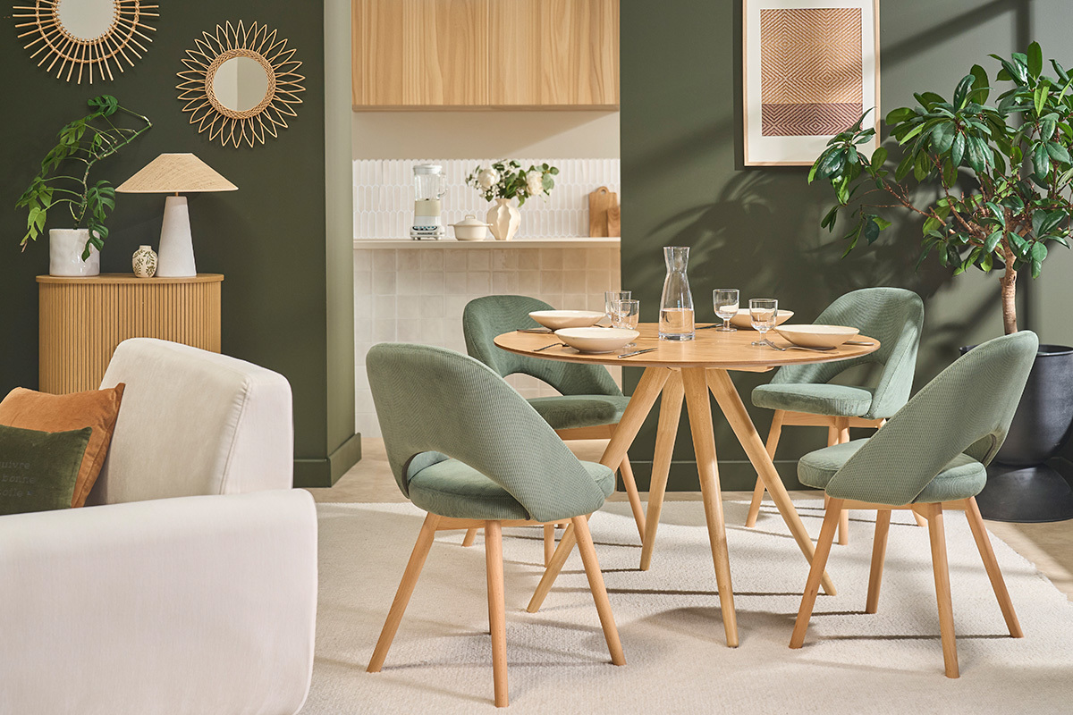 Lot de chaises scandinaves en tissu vert et bois clair, autour d'une table en bois.