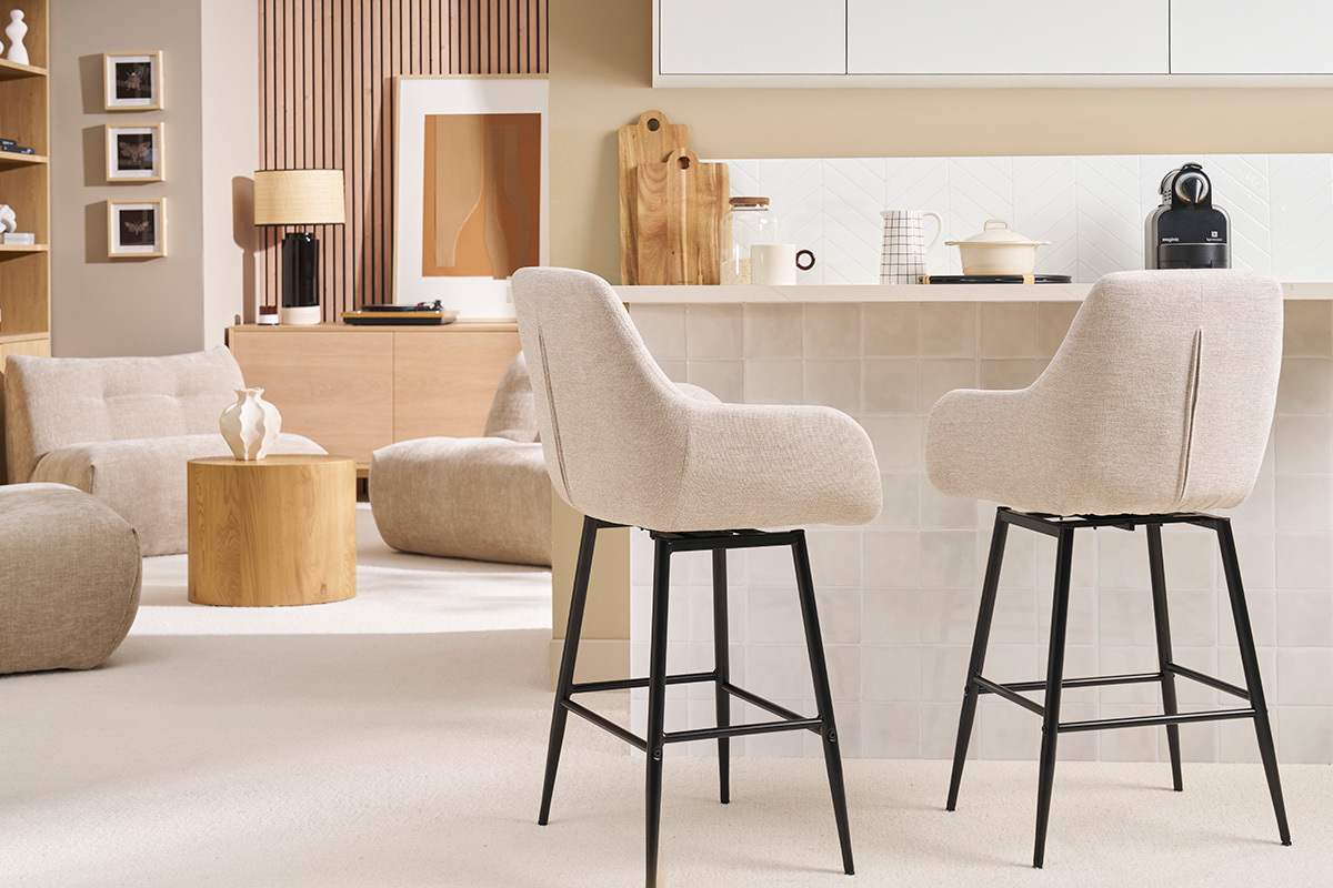 Deux tabourets de bar pivotants effet velours beige avec structure noire, vue de profil, dans une cuisine moderne.