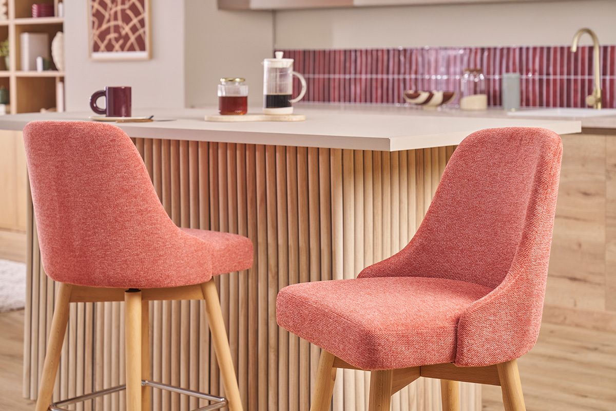 Tabourets de bar scandinaves en tissu terracotta et bois devant un comptoir.
