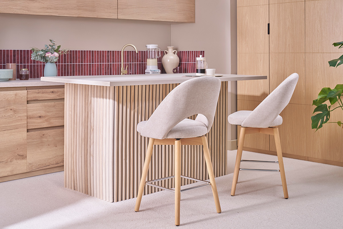 Deux tabourets de bar en tissu beige et pieds en bois dans une cuisine.