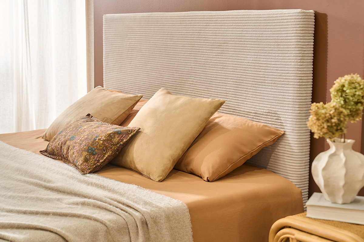 T�te de lit beige en velours c�tel� avec coussins sur lit, vue lat�rale.